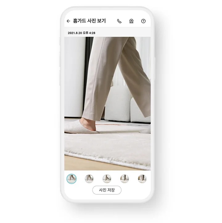 스마트폰 화면에 홈가드 사진 보기라는 제목과 함께 2021년 8월 20일 오후 4시 28분이라는 날짜와 시간이 표시되어 있습니다. 사진에는 베이지색 바지를 입고 실내 슬리퍼를 신은 사람이 카펫 위를 걷고 있는 모습이 담겨 있습니다. 화면 하단에는 여러 개의 작은 사진 미리보기가 있으며, 사진 저장 버튼이 보입니다.